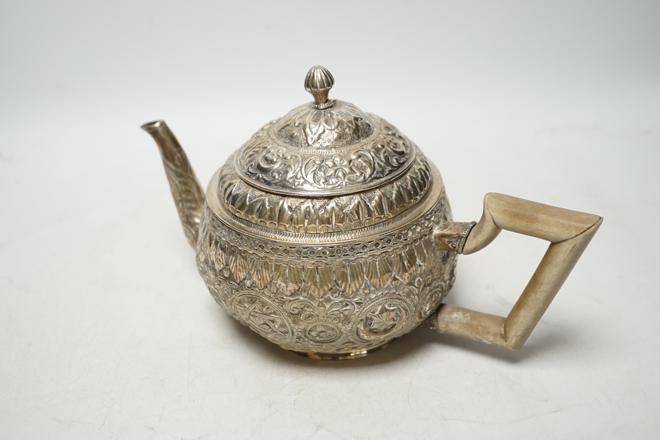 An Indian silver metal teapot with embossed and chased decoration, gross weight 16.9oz. Condition - poor to fair